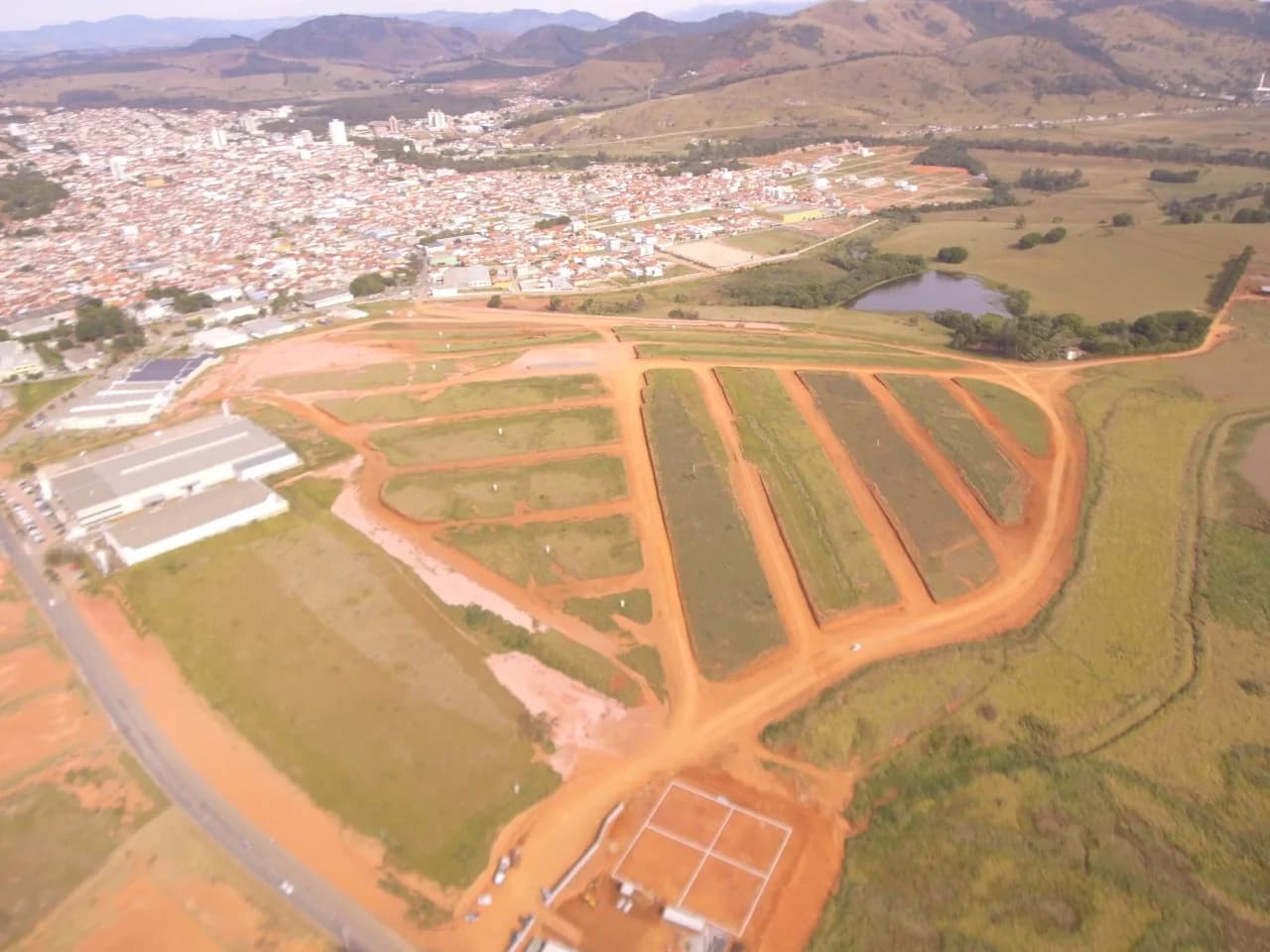 Vista aérea do loteamento em terraplanagem com a cidade ao fundo